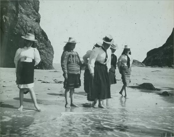 Six ladies paddling on the beach, Perranporth Arch Rock, Cornwall. Around 1925