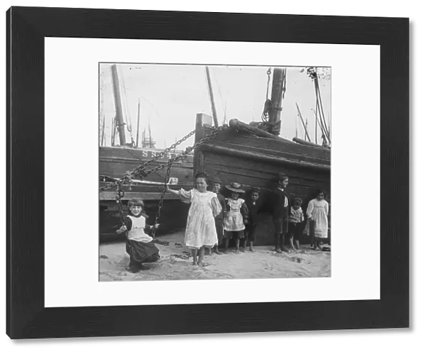 A group of children with fishing vessels at St Ives harbour, Cornwall. Early 1900s