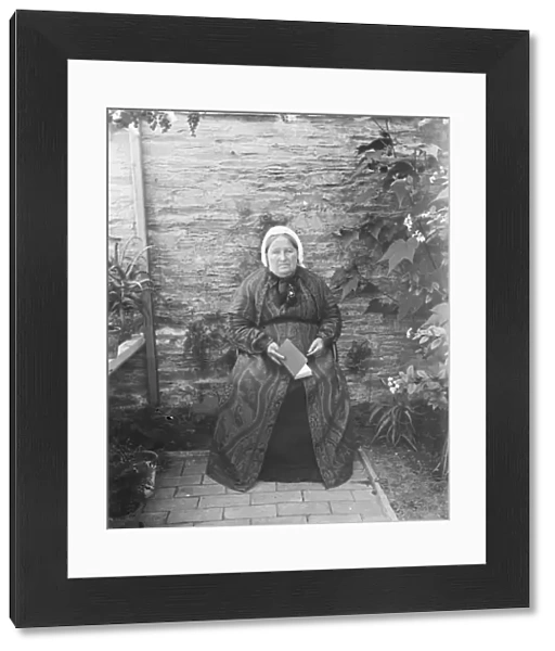 Elderly lady seated by a wall. Padstow, Cornwall. Probably 1890s or early 1900s