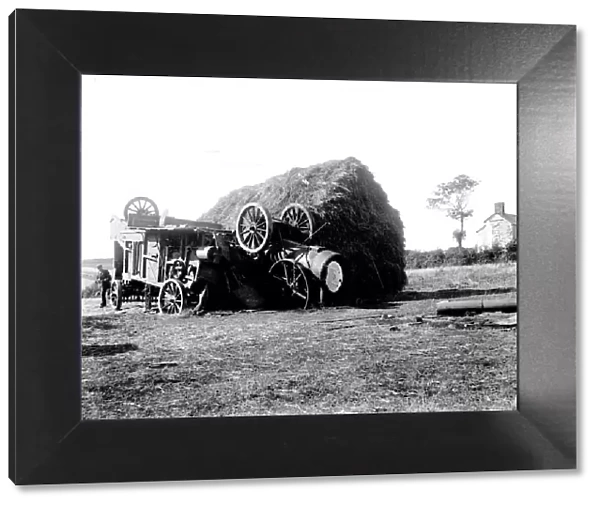 Threshing machine in collision with a hayrick. Possibly in St Stephen in Brannel, Cornwall. Around 1912