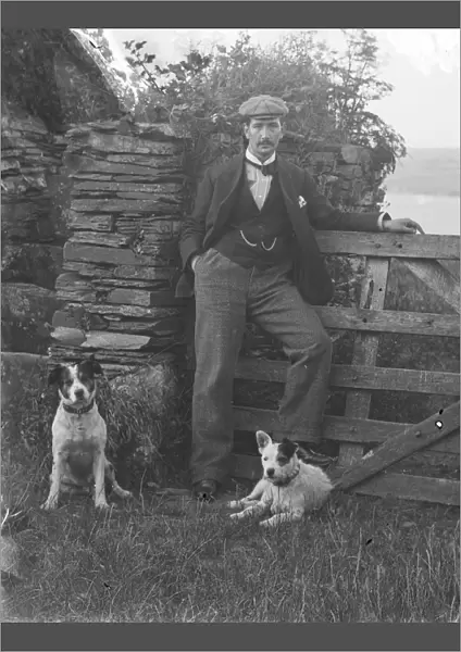 Man with two dogs posed by gateway at St Saviours Point, Padstow, Cornwall. Early 1900s