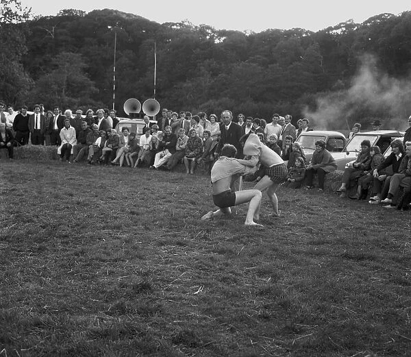 A crowd of people gathered to watch a Cornish wrestling match at an unknown location, Cornwall. 1970