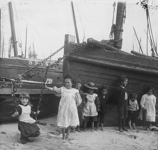 A group of children with fishing vessels at St Ives harbour, Cornwall. Early 1900s