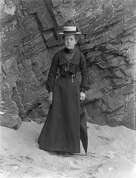 Lady standing below cliff at Padstow, Cornwall. Probably 1890s or early 1900s