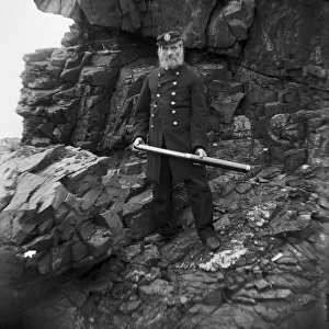 Coastguard with telescope below cliff, Padstow, Cornwall. Early 1900s
