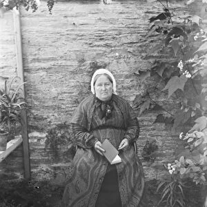 Elderly lady seated by a wall. Padstow, Cornwall. Probably 1890s or early 1900s