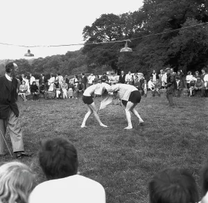 A crowd of people gathered to watch a Cornish wrestling match at an unknown location, Cornwall. 1970