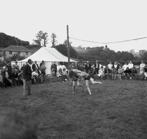 A crowd of people gathered to watch a Cornish wrestling match at an unknown location, Cornwall. 1970