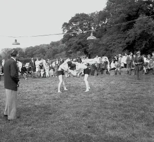 A crowd of people gathered to watch a Cornish wrestling match at an unknown location, Cornwall. 1970