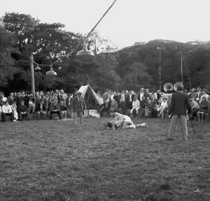 A crowd of people gathered to watch a Cornish wrestling match at an unknown location, Cornwall. 1970