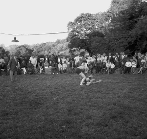 A crowd of people gathered to watch a Cornish wrestling match at an unknown location, Cornwall. 1970