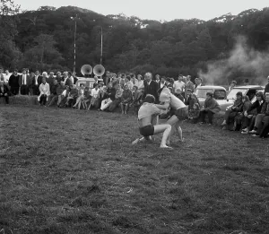 A crowd of people gathered to watch a Cornish wrestling match at an unknown location, Cornwall. 1970