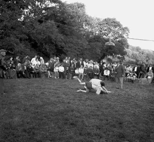 A crowd of people gathered to watch a Cornish wrestling match at an unknown location, Cornwall. 1970