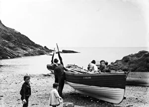 Portloe Collection: Fishermen launching a boat at Portloe, Veryan, Cornwall. July 1912